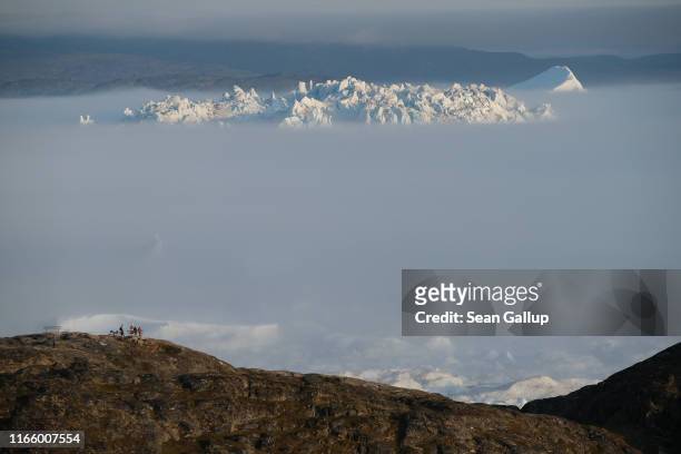 Massive iceberg peeks out from fog in the Ilulissat Icefjord during a week of unseasonably warm weather on August 3, 2019 near Ilulissat, Greenland....