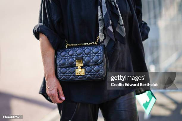 Guest wears a black flowing jacket, a grey and black scarf, a black Dior bag, outside Miu Miu Club 2020, on June 29, 2019 in Paris, France.