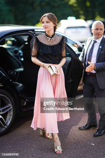 Guest wears a partly transparent black plumetis frilly top, a rhinestone necklace, a pink pleated skirt, a lustrous golden color Miu Miu bag,...