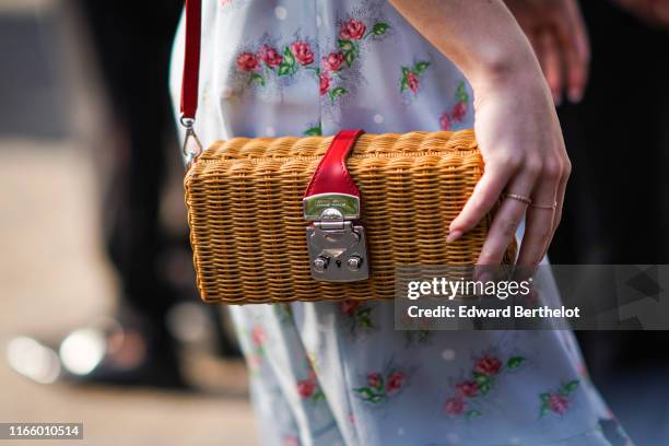 Guest wears a light grey flowing dress with pink and green floral print, a Miu Miu woven wicker bag, outside Miu Miu Club 2020, on June 29, 2019 in...