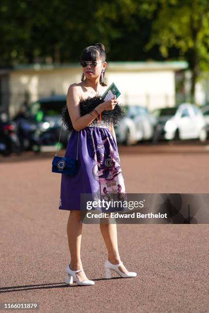 Leaf Greener wears sunglasses, a earrings, a fluffy off-shoulder dress with a printed animal, a blue bag, white shoes, outside Miu Miu Club 2020, on...