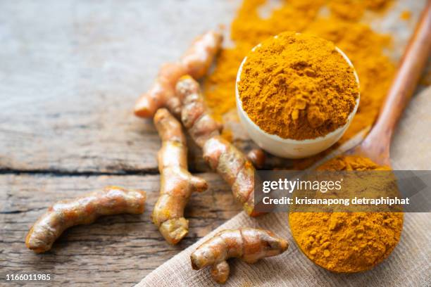 turmeric powder and fresh turmeric on wooden background. - kurkuma stock-fotos und bilder
