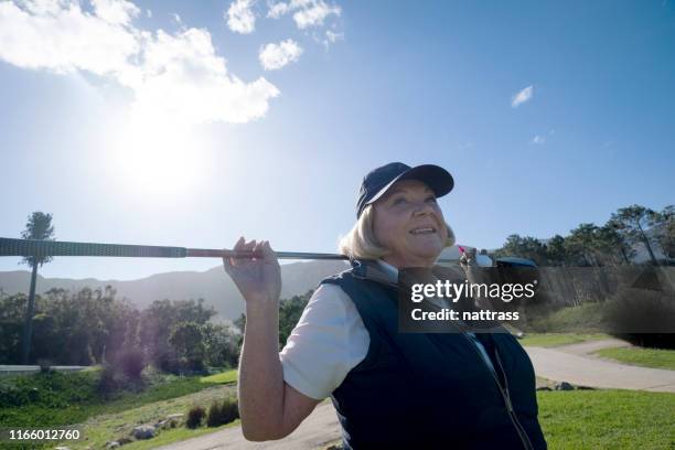 senior female golfer with golf club at course - warm up exercise stock pictures, royalty-free photos & images