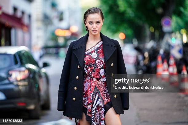 Neta Alchimister wears one earring, a black jacket with brass buttons, a glittering one-shoulder colorfully beaded and sequined peplum tunic ,...