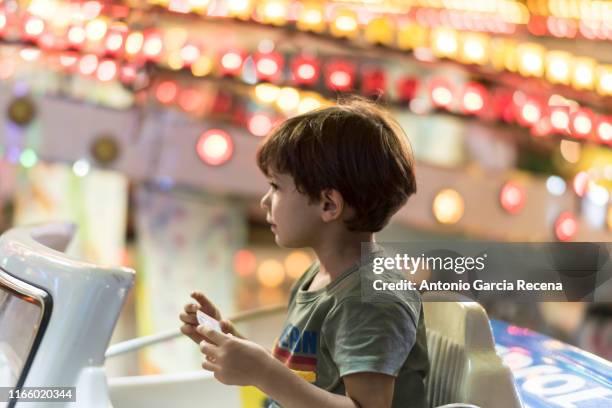 little boy rides at the fairground attractions in amusement park - amusement park ticket stock pictures, royalty-free photos & images