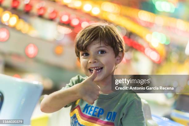 little boy rides at the fairground attractions in amusement park - festival goer stock-fotos und bilder