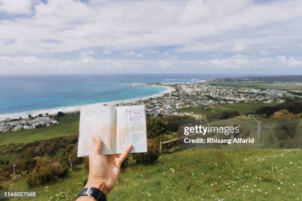 close-up hand holding passport against beach - australian passport bildbanksfoton och bilder