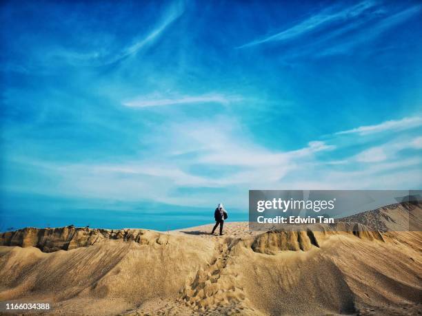 un uomo con cappuccio in mezzo al deserto durante il giorno - malacca foto e immagini stock