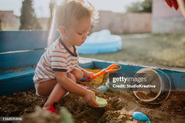 child plays with his single mother in the sandbox - baby sandbox stock pictures, royalty-free photos & images