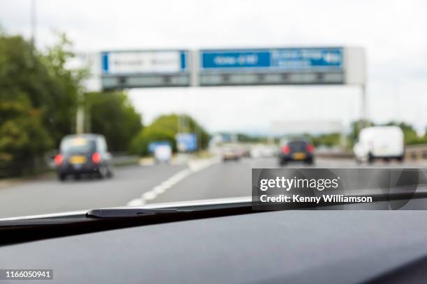 defocused passenger's view through a car windscreen passing a junction on a uk motorway - motorway sign stock pictures, royalty-free photos & images