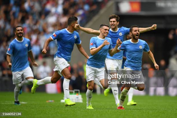 Bernardo Silva, Phil Foden and John Stones of Manchester City celebrate following their team's victory in the penalty shoot out during the FA...
