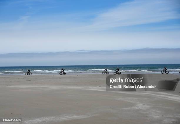 Group of young men ride their fat tire bicycles along the beach near Newport, Oregon.