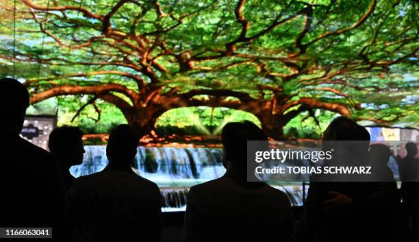 People watch a television installation at the booth of LG during a press preview at the international electronics and innovation fair IFA in Berlin...