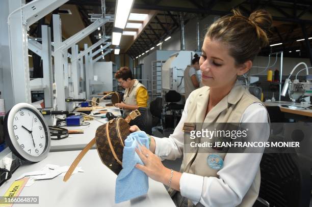 An employee checks a leather bag in the Louis Vuitton workshop in