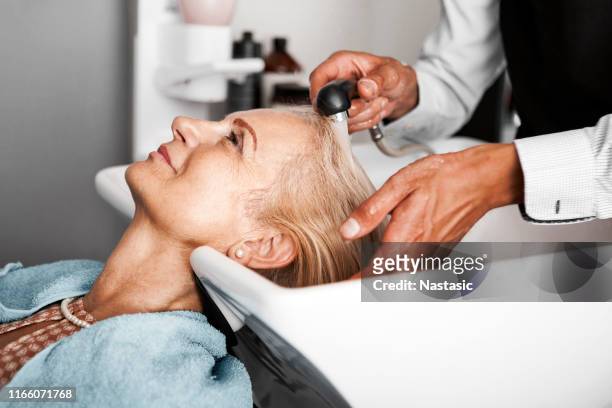 hair stylist washing mature woman hair - cabeleireiro imagens e fotografias de stock