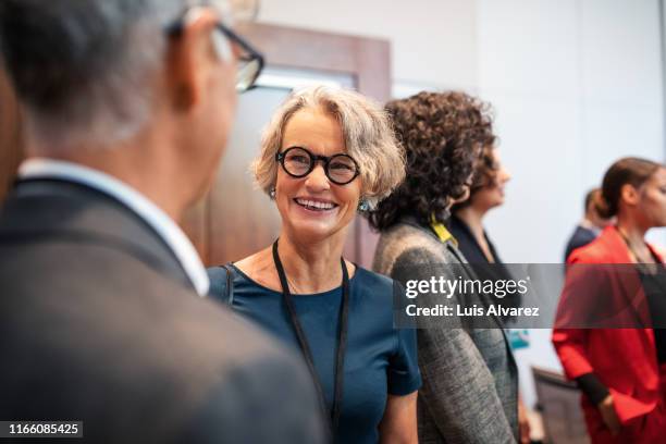 business professionals having a casual chat before a launch event - business conference auditorium stockfoto's en -beelden