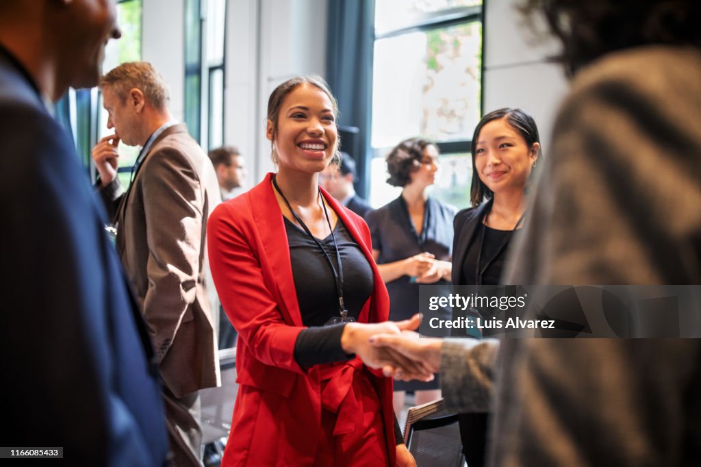 Businesswomen handshaking in auditorium corridor