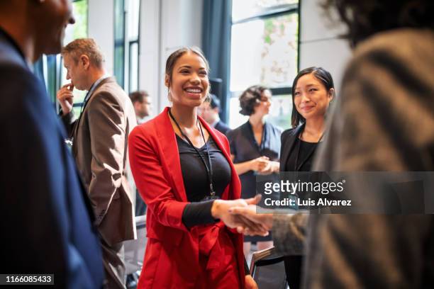 businesswomen handshaking in auditorium corridor - teilnehmen stock-fotos und bilder