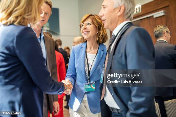 business people greeting each other in convention center - meet and greet stock-fotos und bilder