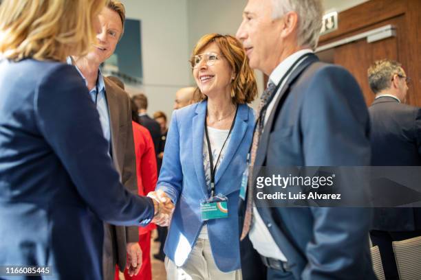 business people greeting each other in convention center - attending event stock pictures, royalty-free photos & images