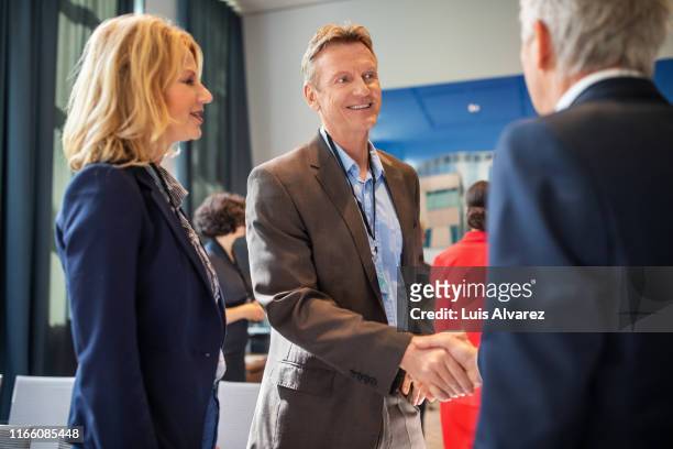 corporate professionals greeting each other at auditorium - meet and greet stock-fotos und bilder