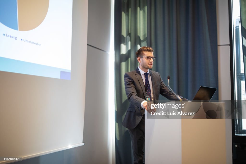 Confident businessman giving presentation during conference