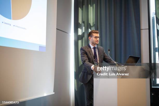 confident businessman giving presentation during conference - lectern stock pictures, royalty-free photos & images