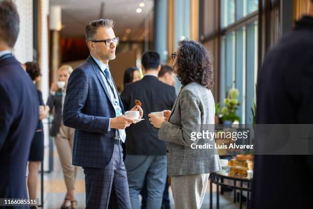 business professionals during a coffee break in auditorium - businesswoman hotel stock pictures, royalty-free photos & images