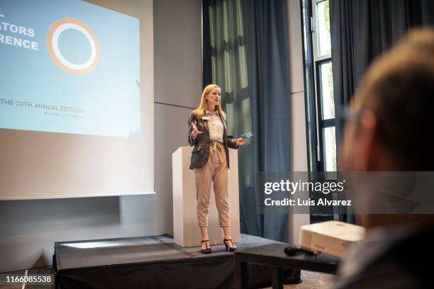 female professional giving presentation in a conference - ponencia fotografías e imágenes de stock