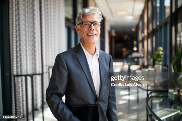 portrait of senior businessman in hotel corridor - businessman hotel ストックフォトと画像