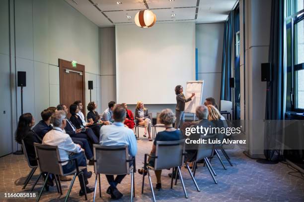 businesswoman explaining strategy over a flip chart - multicultural round launch stock-fotos und bilder