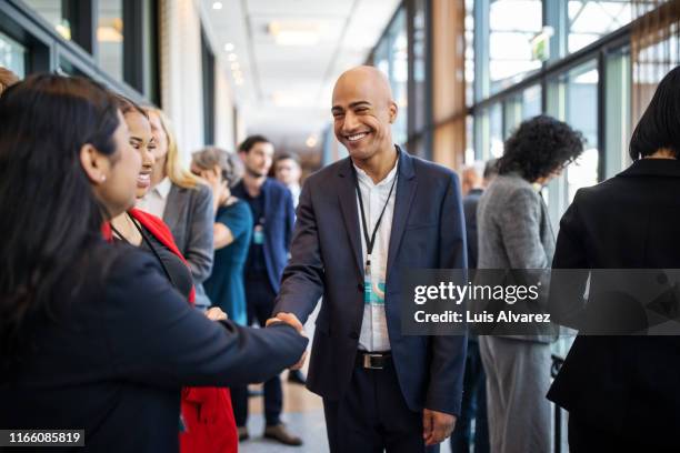 business executives handshaking at convention center - international conference stock pictures, royalty-free photos & images