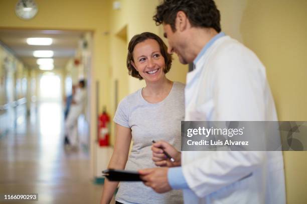 doctor talking with a woman in hospital corridor - sharing good news stock pictures, royalty-free photos & images