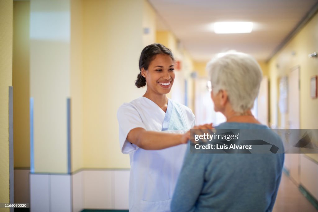 Nurse consoling a senior woman in hospital hallway