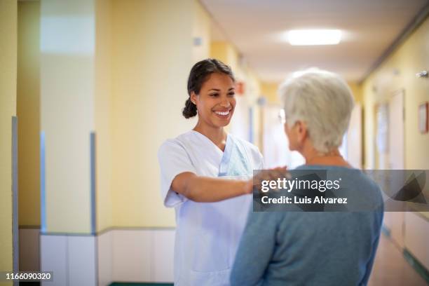 nurse consoling a senior woman in hospital hallway - mutual respect stock pictures, royalty-free photos & images