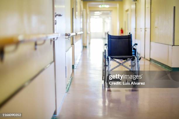 empty wheelchair in hospital corridor - krankenhaus niemand stock-fotos und bilder