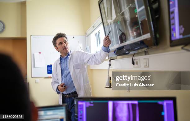 doctors discussing over x-ray reports on a digital display - tv test stock pictures, royalty-free photos & images