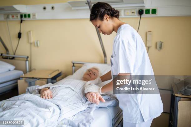 health carer taking care of an elderly patient in hospital - hospital visit stock-fotos und bilder