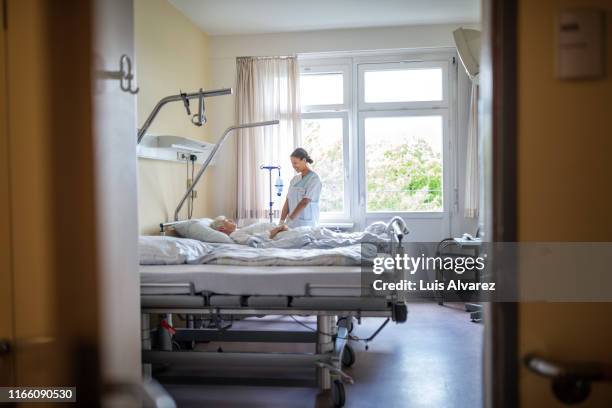 nurse doing routine check up of senior patient - hospital ward stock-fotos und bilder