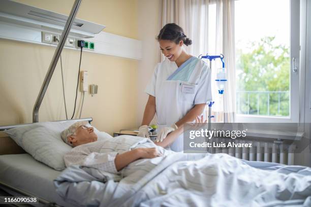 nurse giving iv drip on patient arm - hospital bed with iv stock pictures, royalty-free photos & images