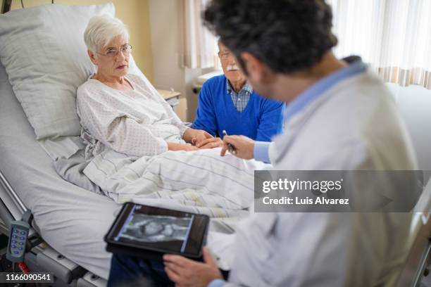 doctor explaining the knee replacement treatment to senior patient - man touching womans leg fotografías e imágenes de stock