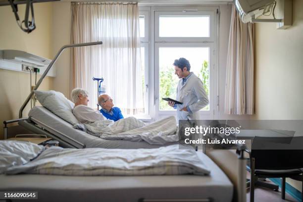 doctor during a routine check up of a senior patient - krankenbett gespräch stock-fotos und bilder