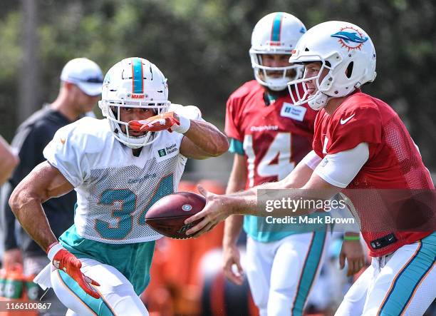 Jake Rudock hands the ball to Kenneth Farrow of the Miami Dolphins in practice drills during training camp at Baptist Health Training Facility at...