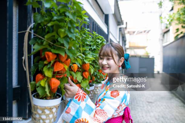 路上で冬の桜に触れる浴衣の幸せな若い女性 - chinese lanterns ストックフォトと画像