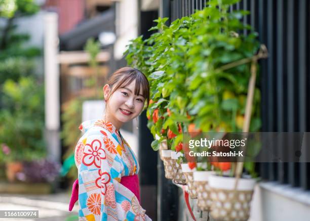young woman in yukata standing on street with winter cherries - winter cherry stock pictures, royalty-free photos & images