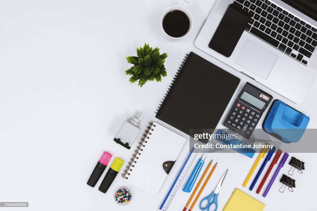 Top View of Laptop, Notebook, Coffee and Office Supply Items on White Desk