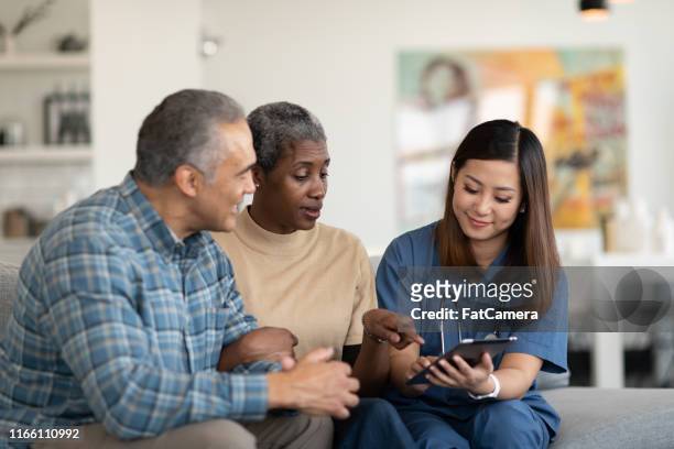sharing results with an elderly couple - couple doctor stock pictures, royalty-free photos & images