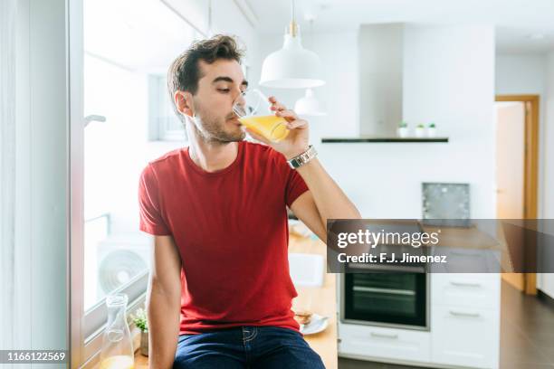 man with orange juice at home - orangensaft stock-fotos und bilder