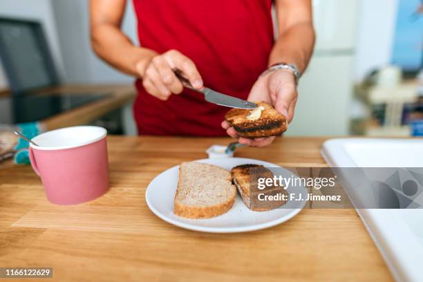 man smearing butter on toast - untar de mantequilla fotografías e imágenes de stock