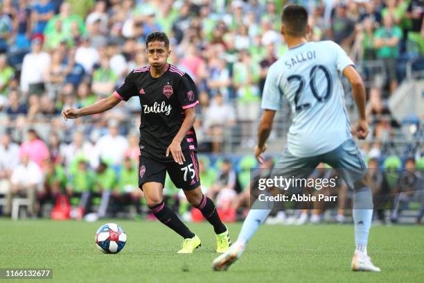 Danny Leyva of Seattle Sounders dribbles with the ball against Daniel Salloi of Sporting Kansas City in the first half during their game at...